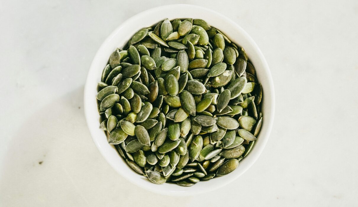A bowl filled with fresh green pumpkin seeds, ideal for healthy eating.