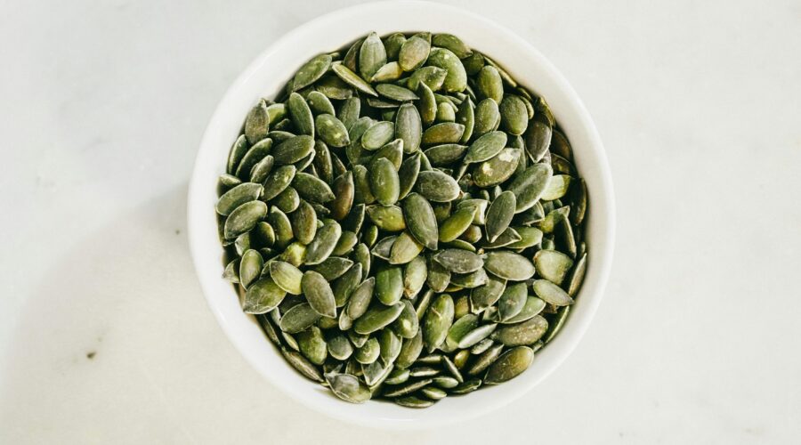 A bowl filled with fresh green pumpkin seeds, ideal for healthy eating.